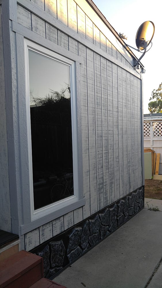 Exterior remodel with white siding and rock skirting