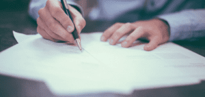 Man signing a document with pen in hand