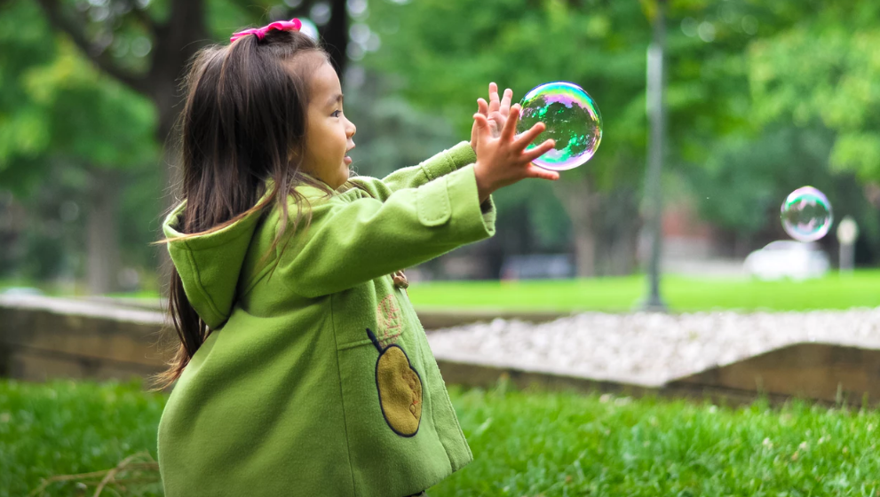 little girl playing with bubbles in the park