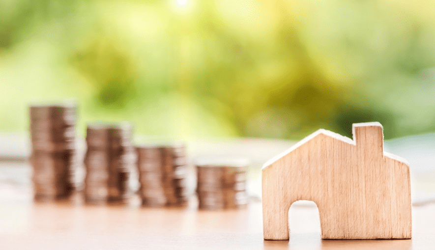 home investment illustrated with coins and wooden house figurine