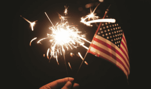 person holding a firework and a small American flag