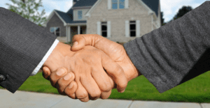 Two gentlemen shaking hands in front of a house