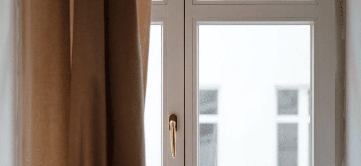 A white window frame with a golden handle