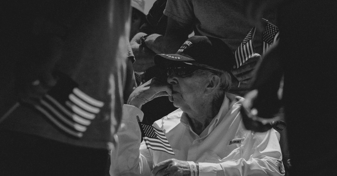 Old veteran sitting down holding a small US flag