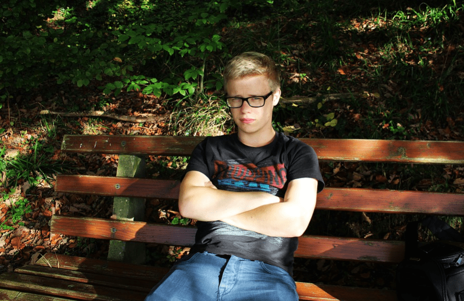 A young male sitting on a bench, unhappy