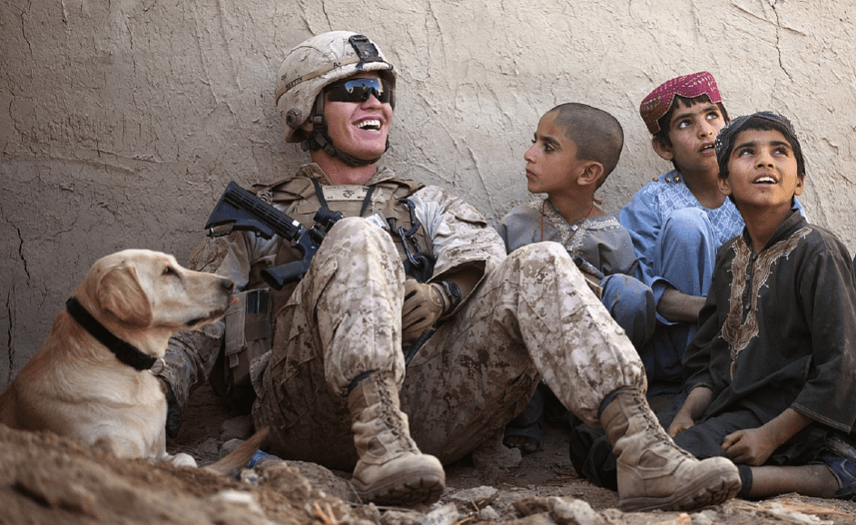 A soldier laughing with children