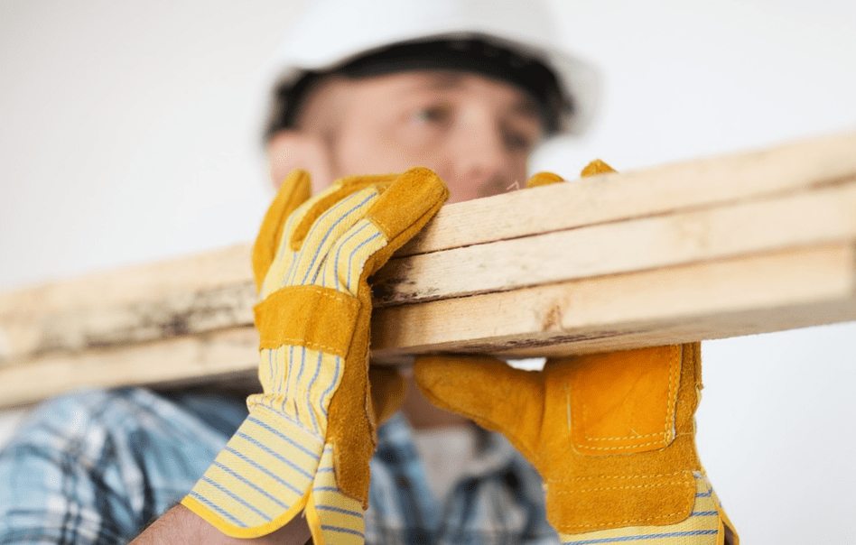 A construction worker carrying wooden beams