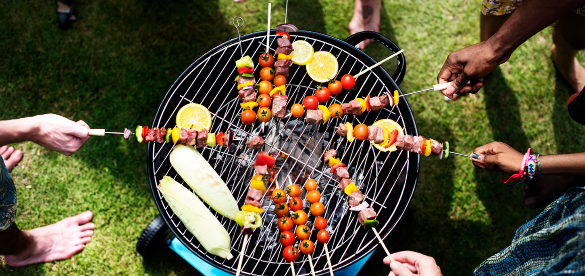 A group of people at a bbq party grilling skewers