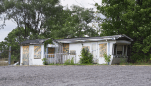 Dilapidated, boarded up mobile home with foreboding graffiti