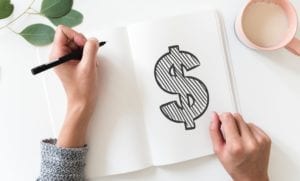 Woman drawing money sign in notebook - Photo by rawpixel on Unsplash