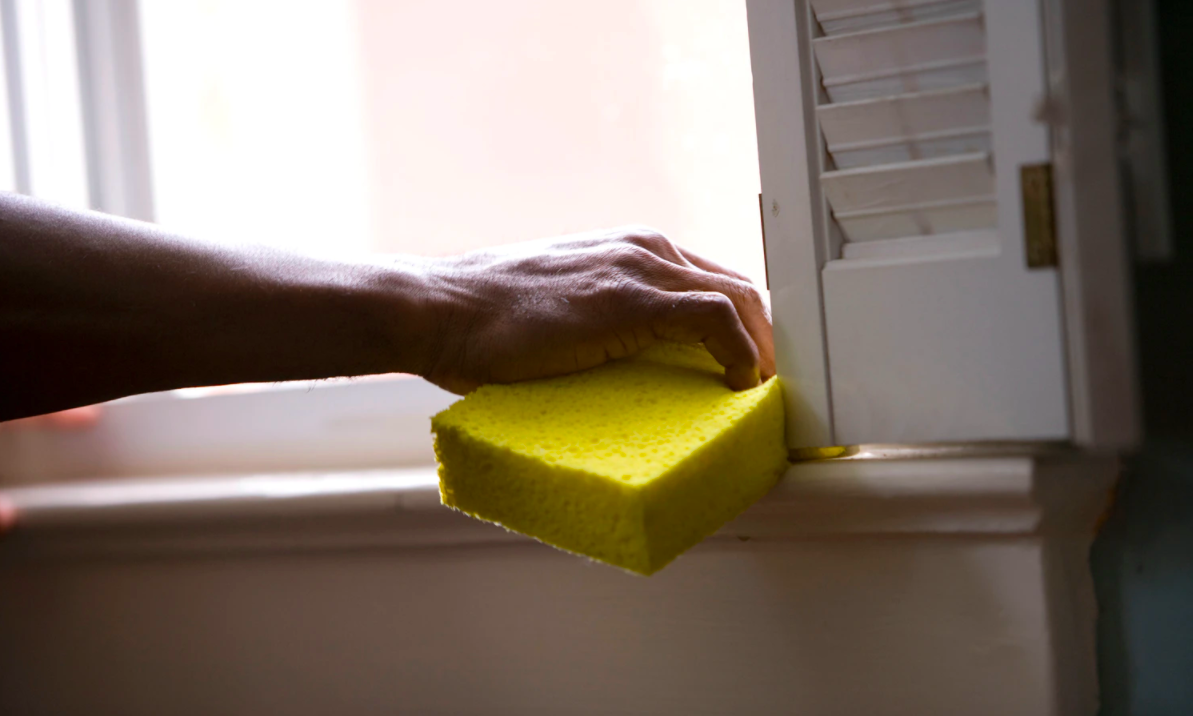 Person cleaning with a yellow sponge